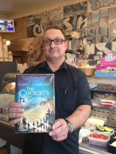 Soner hassan from Phoenix Cafe with the Cuckoo's Calling book by J.K. Rowling