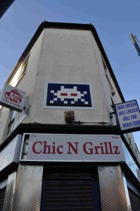 A mosaic piece above a chicken shop, by Invader, on Coldharbour Lane