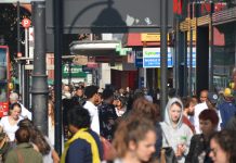 Crowds of people walk down Brixton Road in the sunshine