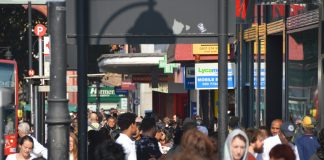 Crowds of people walk down Brixton Road in the sunshine