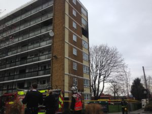 Firefighters stand outside the charred flat after bringing the blaze under control