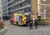Fire crew stand next to burnt Effra Road flat