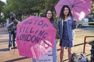 Stop Killing Londoners protest. Young women with umbrella slogans