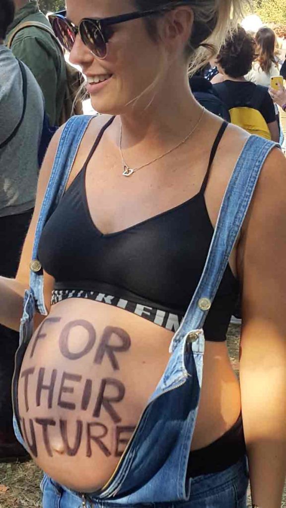 Pregnant women with climate slogan on stomach