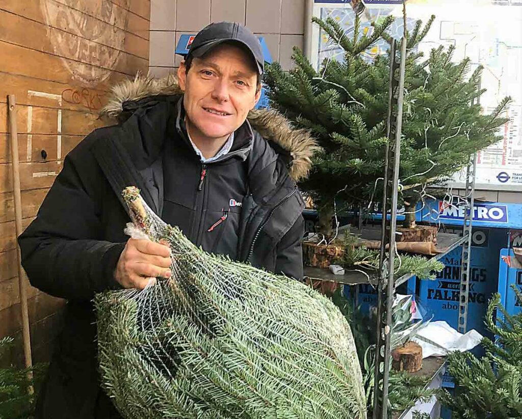 man with packaged Christmas tree