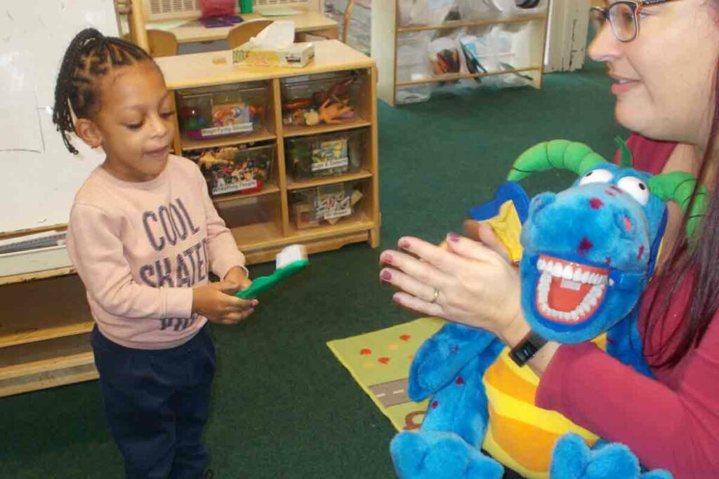 child with giant toothbrush in nursery