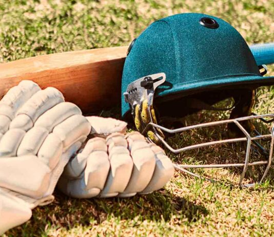 cricket bat, gloves and helmet on grass