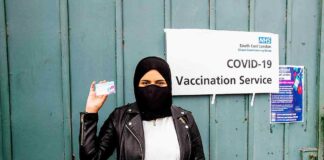 woman at vaccination centre displays vaccine record card