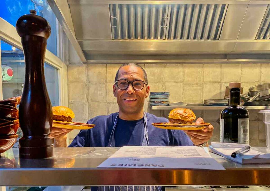 chef at servers hatch with burger