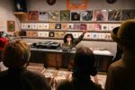 woman selector in front of crowd in record store