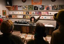 woman selector in front of crowd in record store