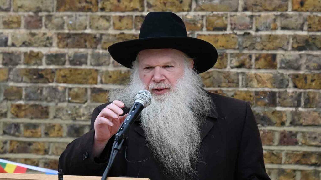 rabbi speaks to mic ay outdoor meeting
