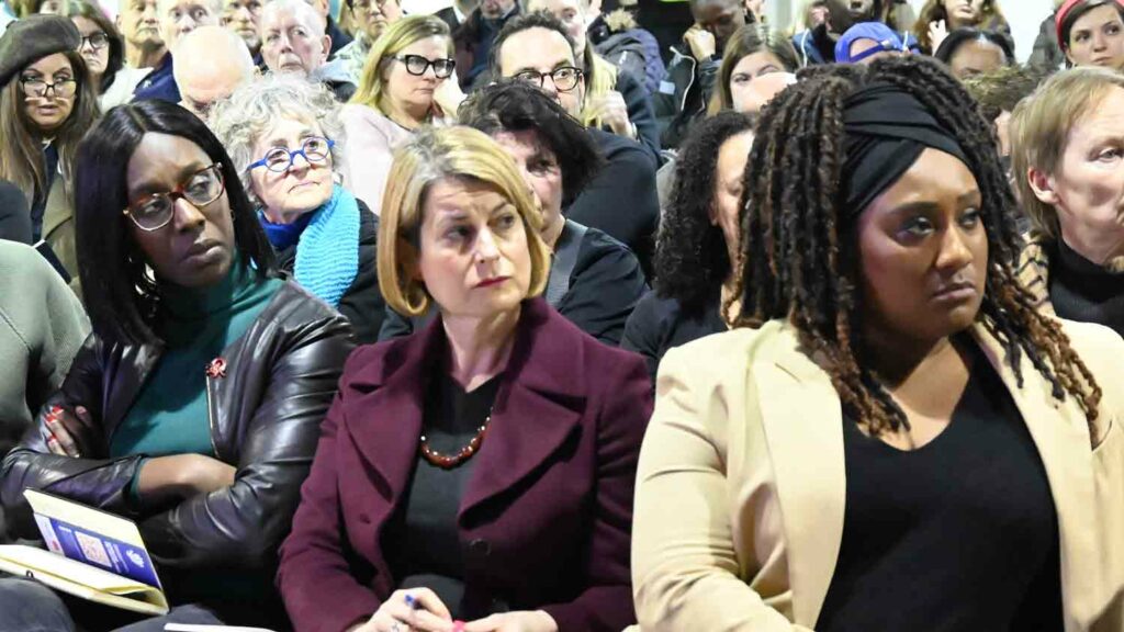 three women in audience at public meeting