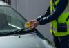 warden attaching parking ticket to windscreen