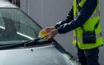 warden attaching parking ticket to windscreen