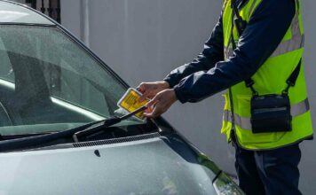 warden attaching parking ticket to windscreen