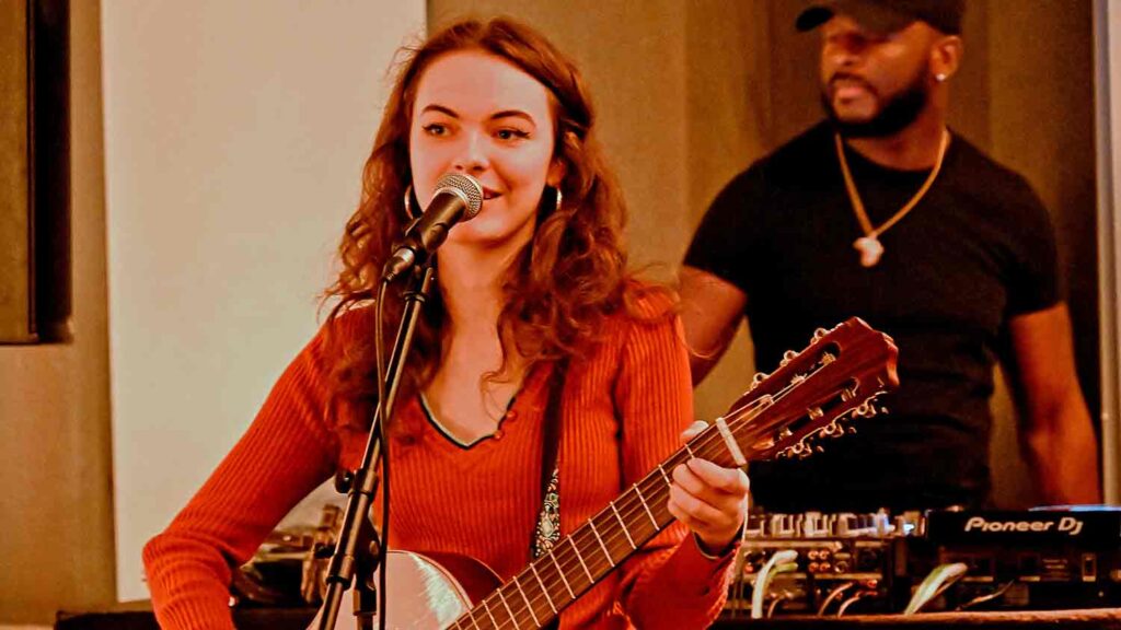 young woman playing guitar and singing into mic