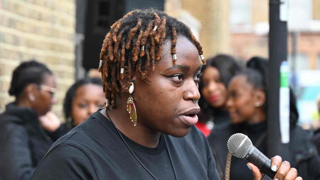 woman speaking into mic at public open air event