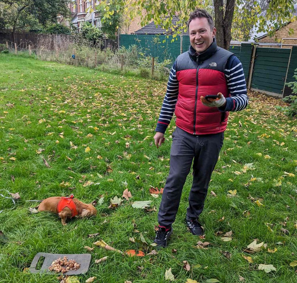 man with plant bulbs and small dog